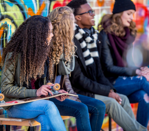 A group of young people of different ethnicities and genders at a skate park.